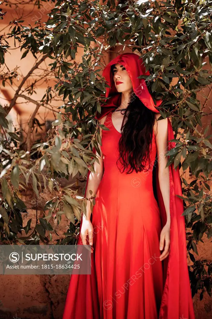 Woman in little red riding hood costume amidst plants