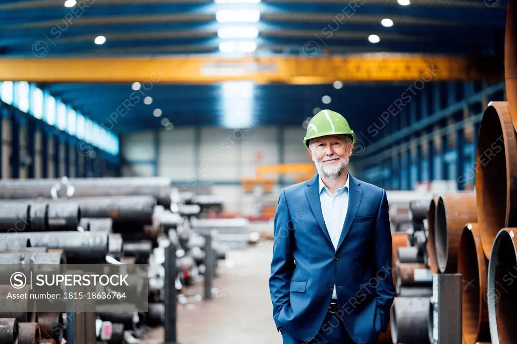 Smiling male managing director standing with hands in pockets at warehouse