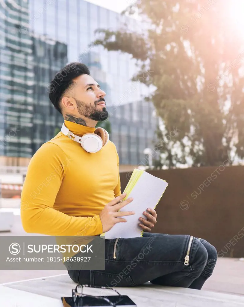 Thoughtful male student with papers in city