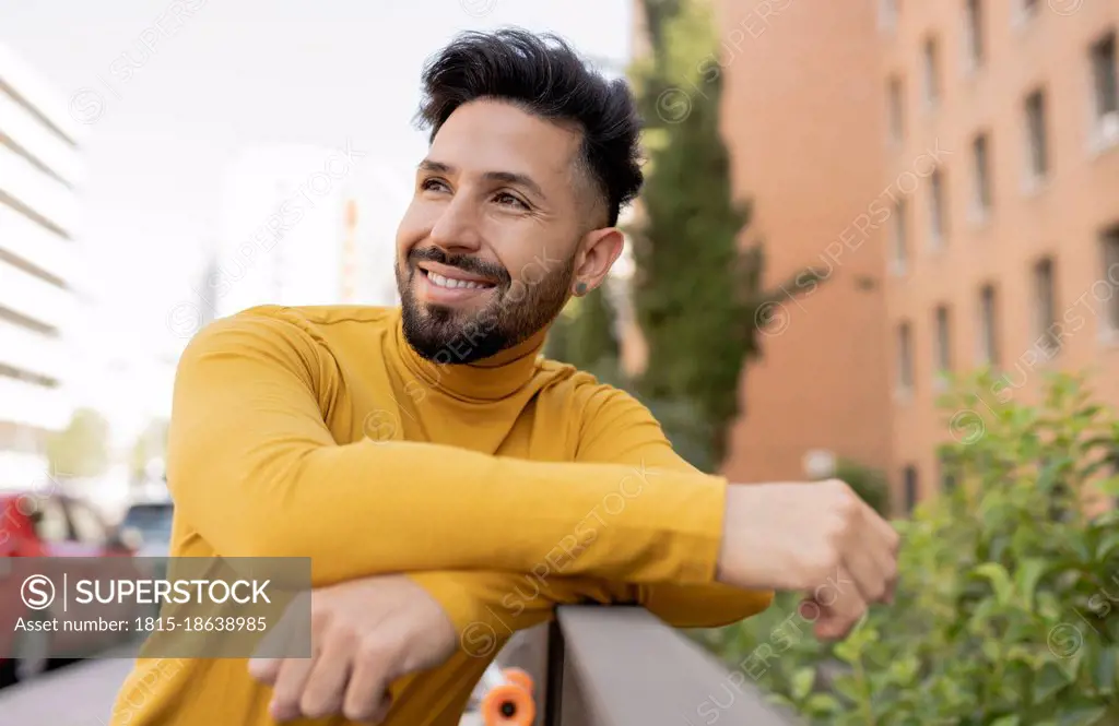 Smiling handsome bearded man leaning on railing