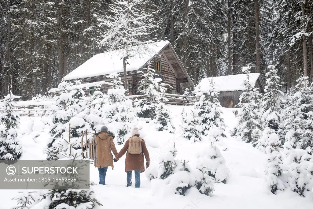 Young couple holding hands while walking on snow