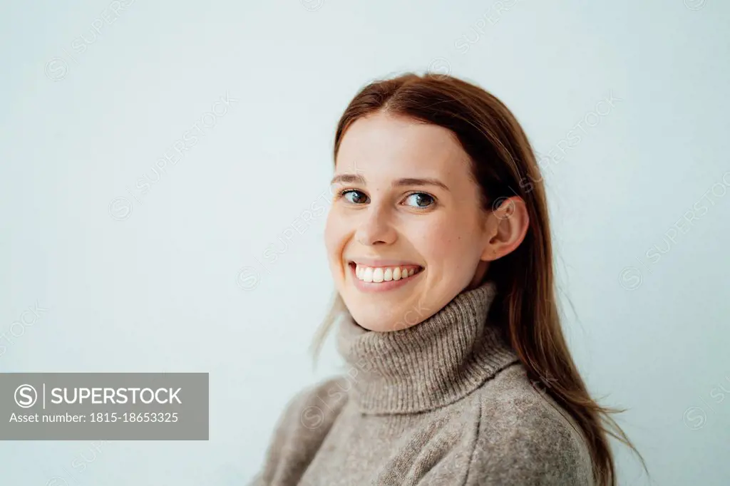 Smiling woman with brown hair by white background