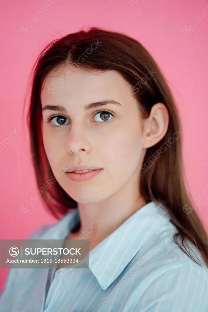 Young woman with long hair against pink background