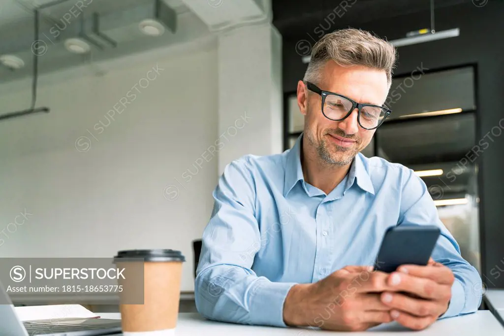 Male business professional using smart phone in office