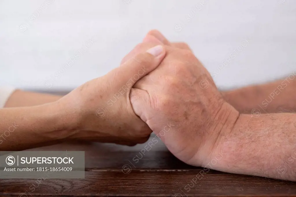 Senior couple holding hands on table