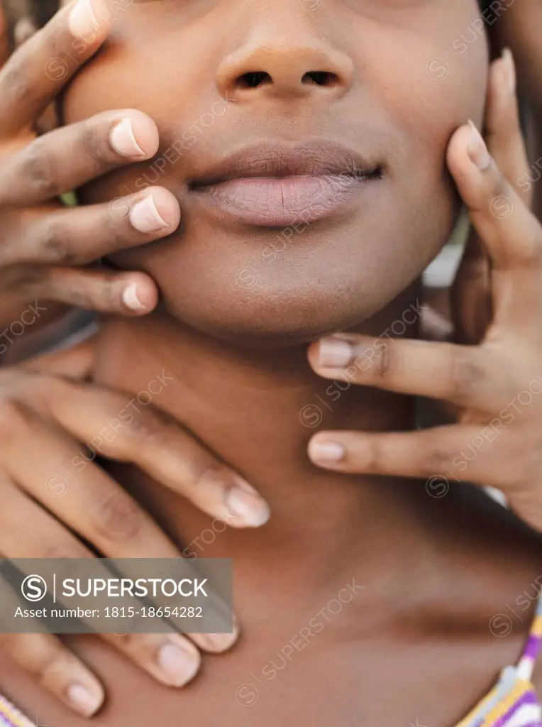 Hands touching face of young woman