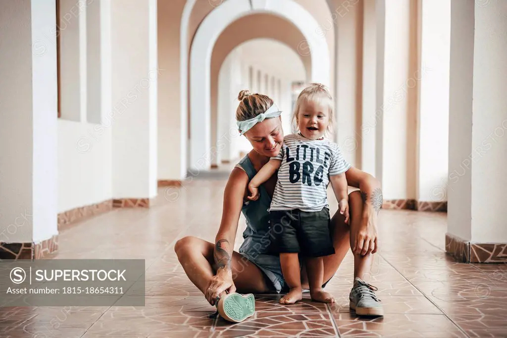 Smiling mother with playful son in corridor