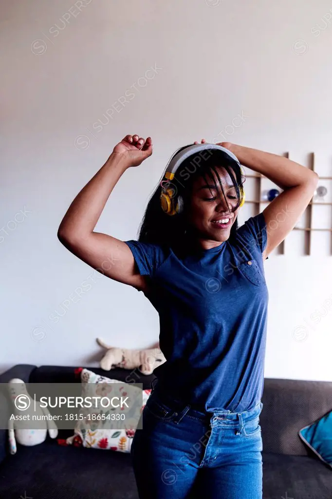 Woman with arms raised dancing in living room