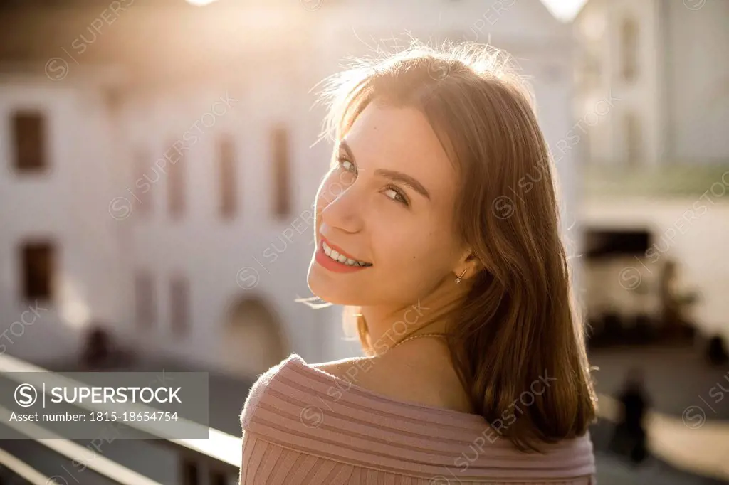 Smiling young woman on rooftop during sunny day