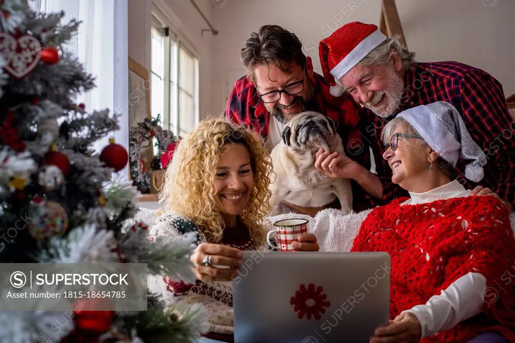 Family with dog attending video call through laptop at home