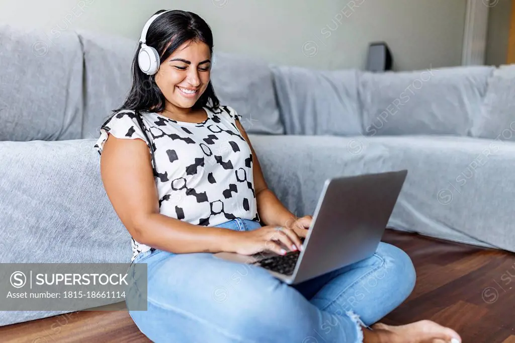 Happy woman using laptop in living room