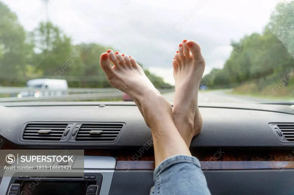 Mature woman with feet up on car dashboard