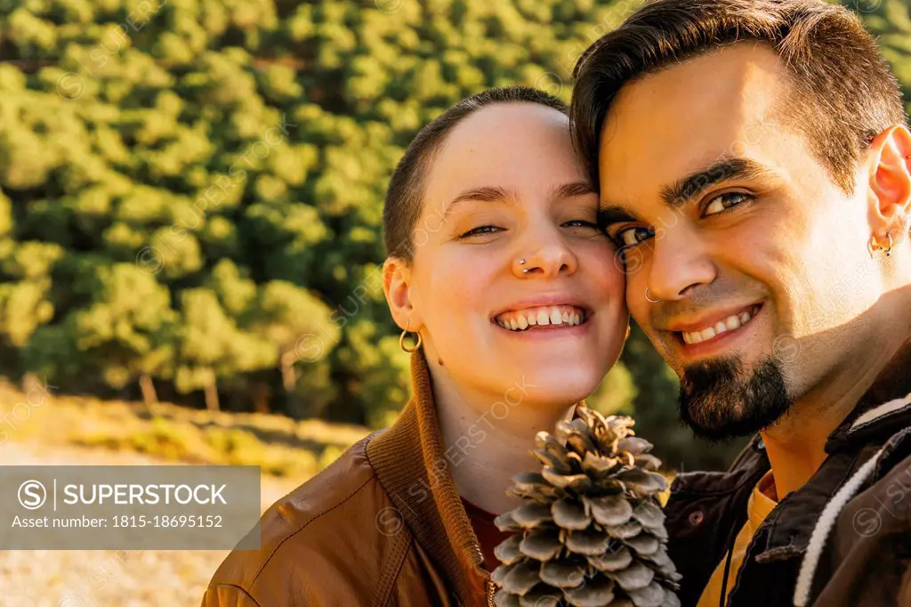 Smiling couple with pine cone on mountain