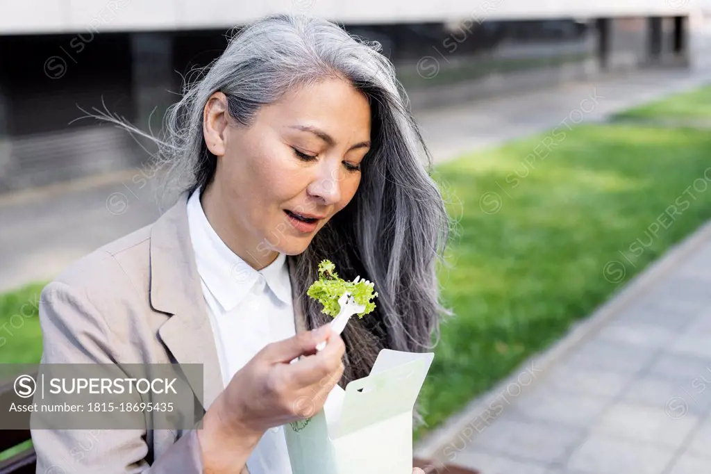 Mature woman eating salad from food box