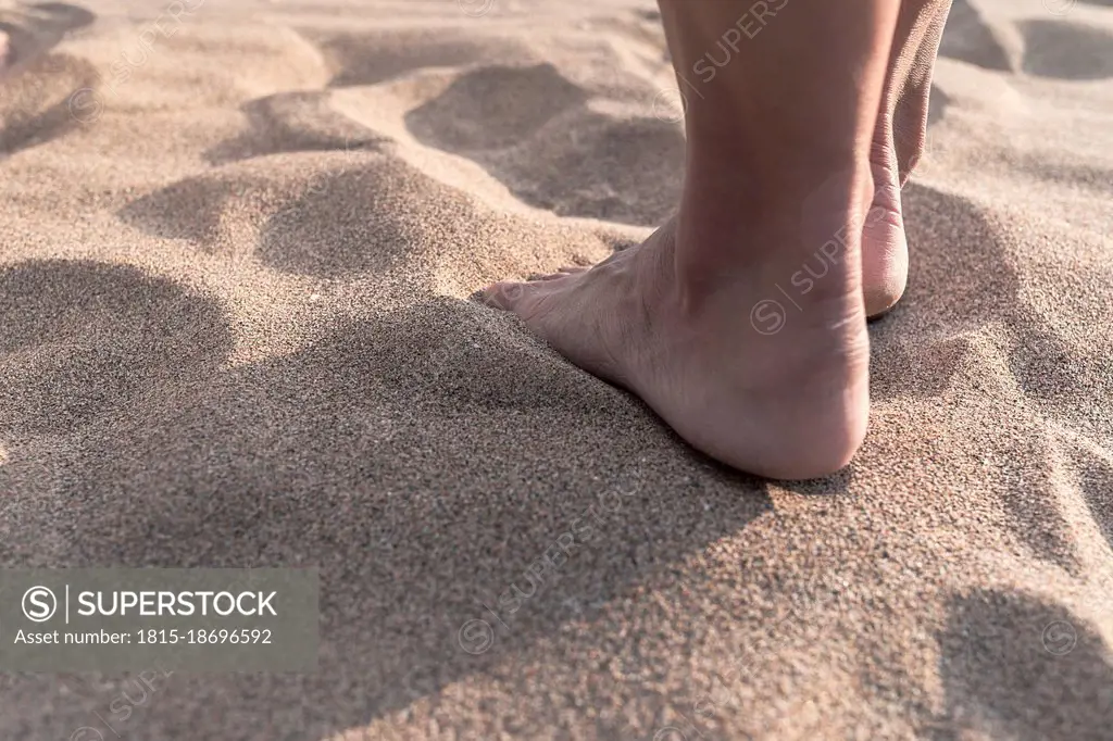 Mature woman with barefoot standing on sand