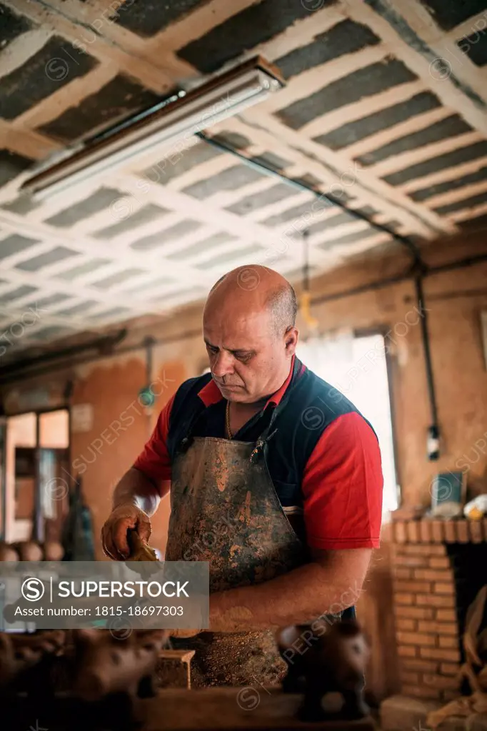 Potter in apron working in pottery