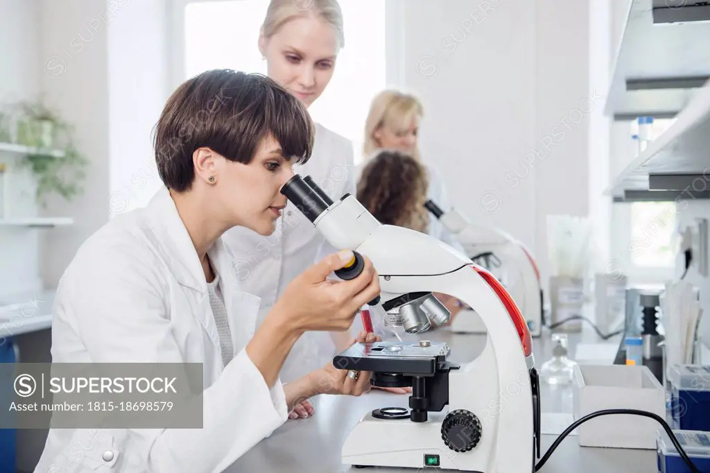 Scientist checking sample through microscope in laboratory