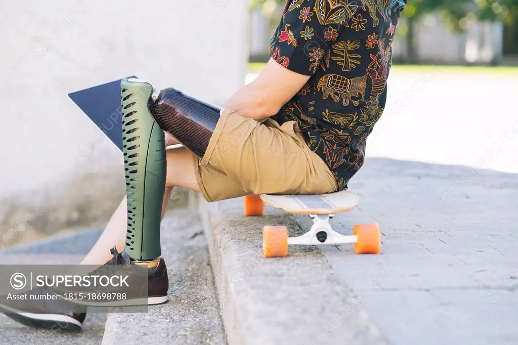 Man with prosthetic leg using laptop on steps