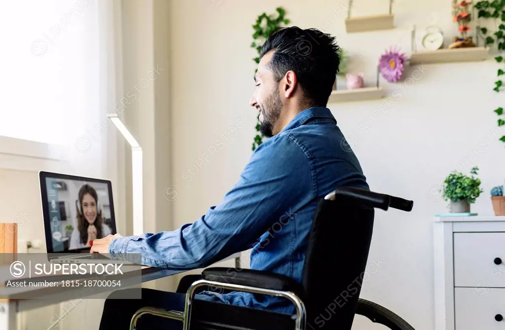 Smiling businessman talking with businesswoman on video conference through laptop at home