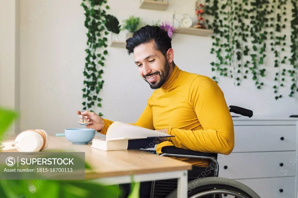 Smiling disable man reading book on wheelchair