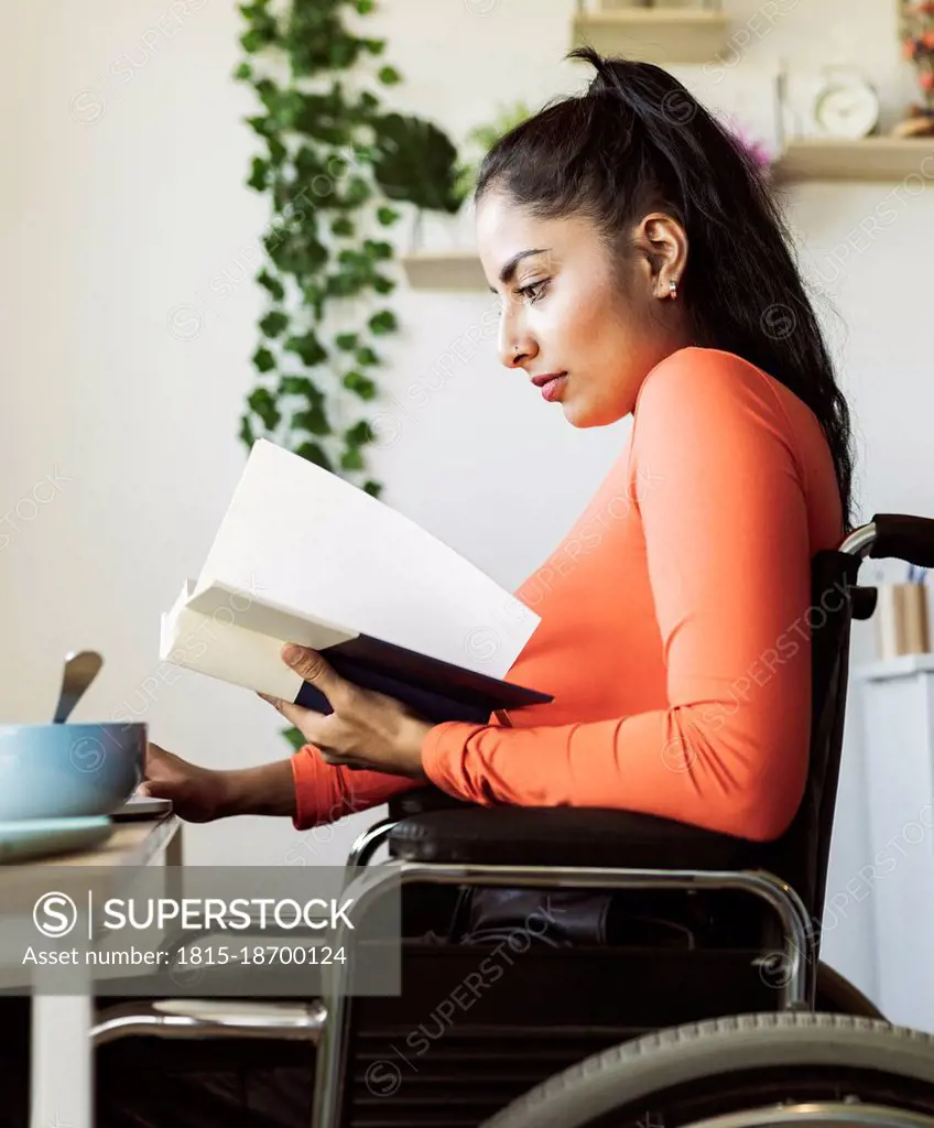 Young disabled woman reading book at home