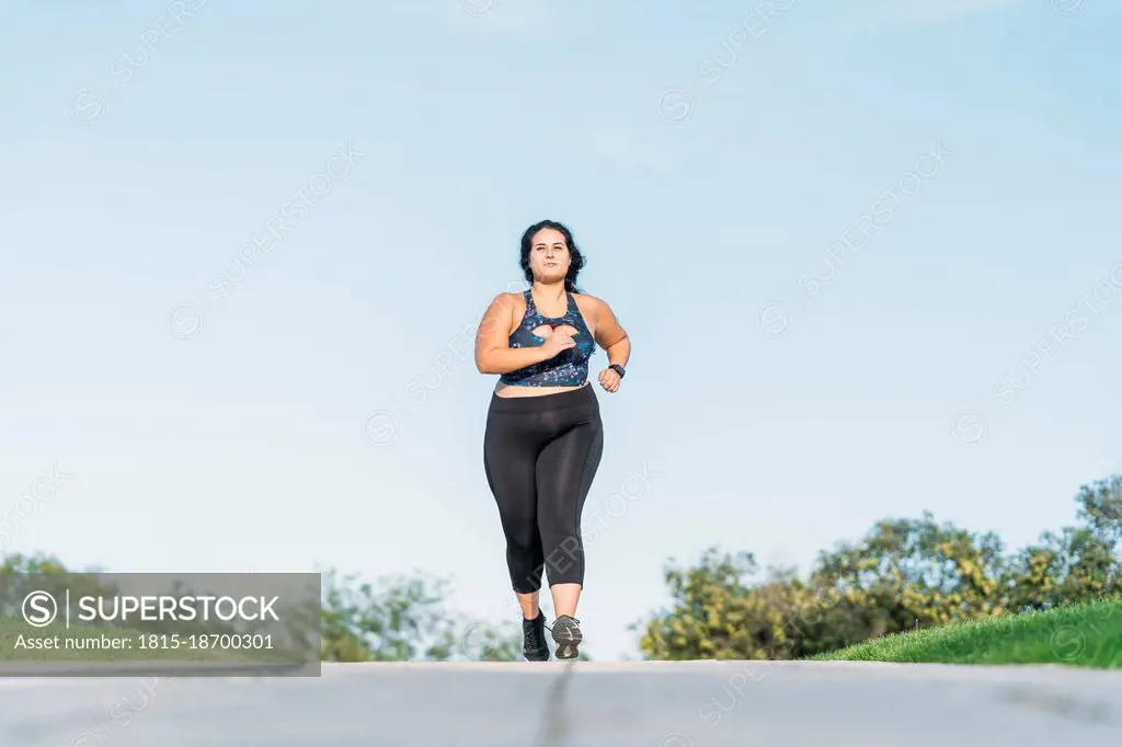 Plus size sportswoman running on road