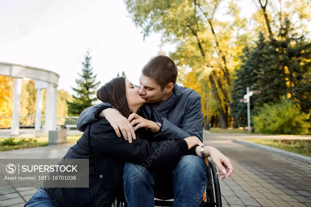 Boyfriend in wheelchair kissing girlfriend in park