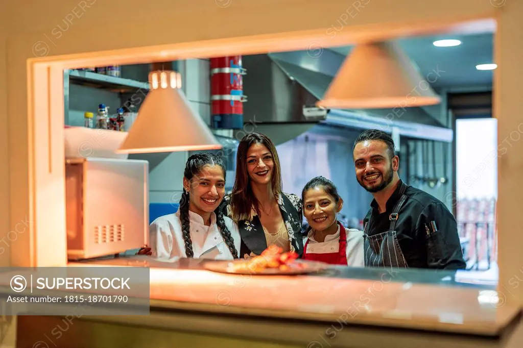 Smiling manager with kitchen team in restaurant