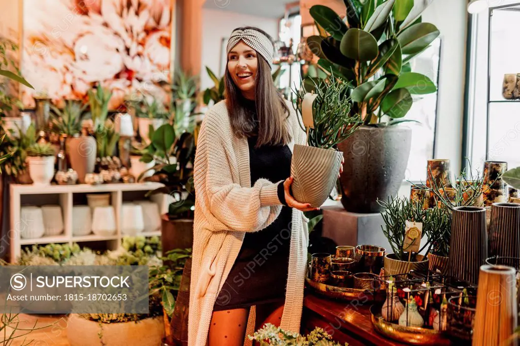 Smiling young woman buying potted plant at flower shop