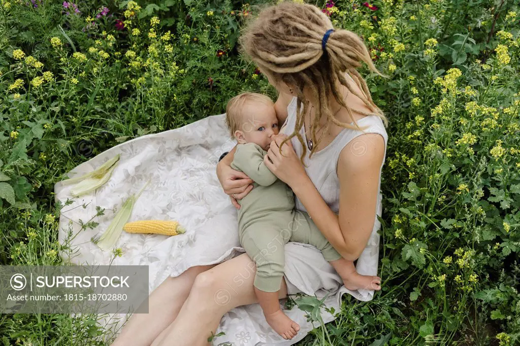 Woman breastfeeding toddler girl amidst flowering plants