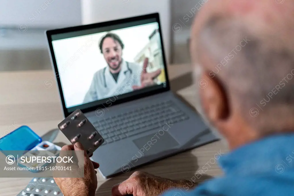 Senior man taking medical advice on video call with doctor at home