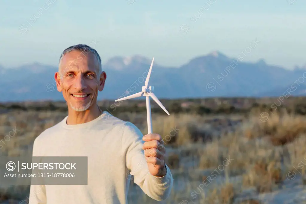 Smiling man holding wind turbine model