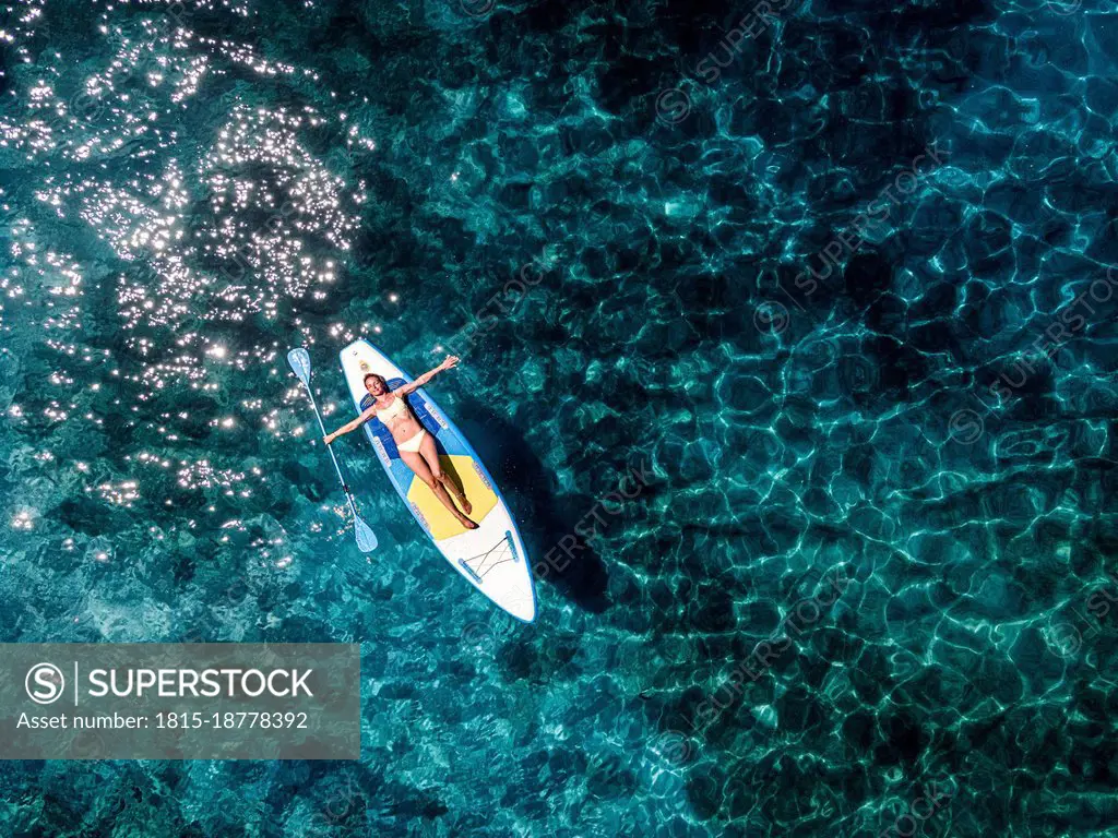 Woman lying on paddleboard in sea during vacation