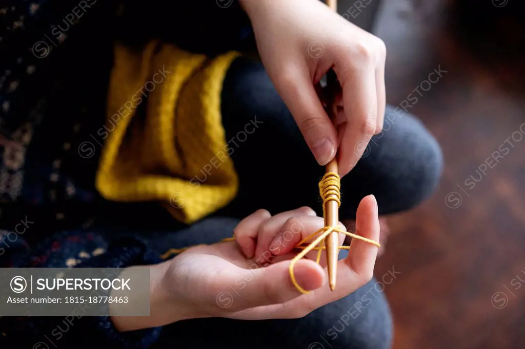 Young woman knitting wool with needle at home