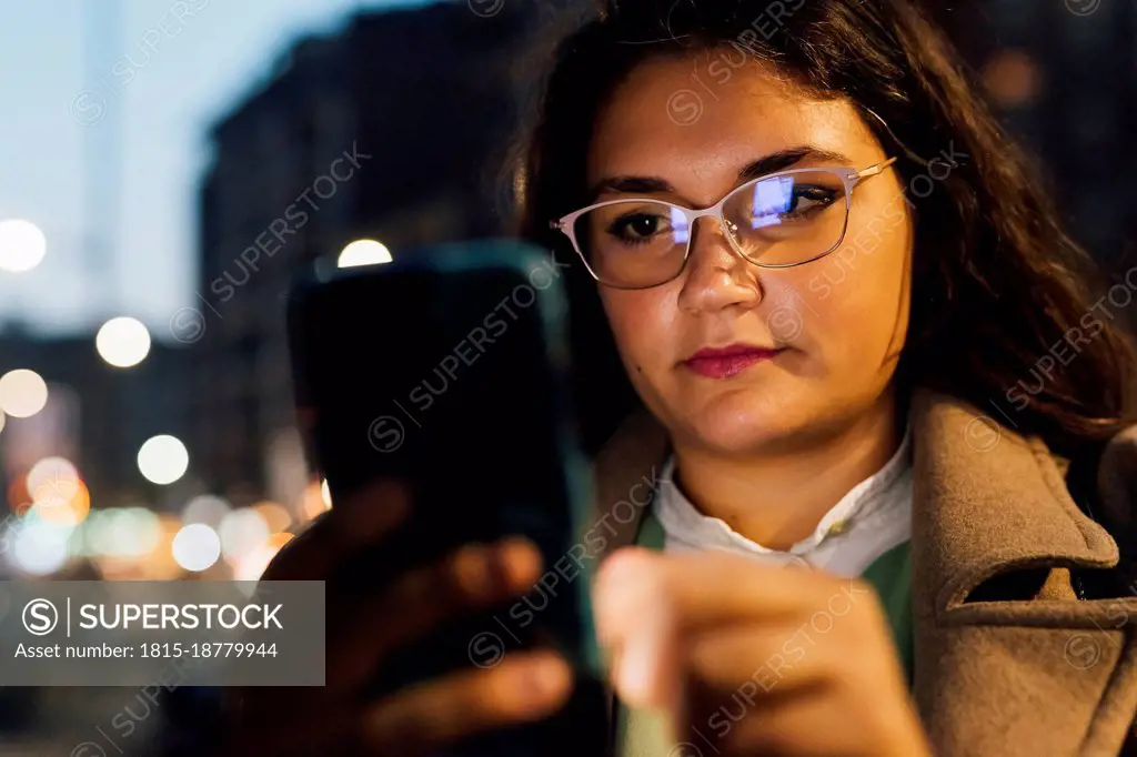Young woman wearing eyeglasses using mobile phone