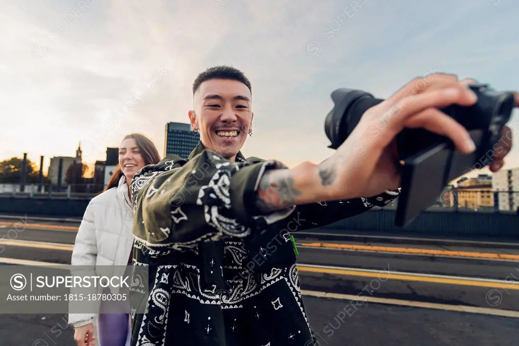 Happy couple taking selfie through digital camera on road