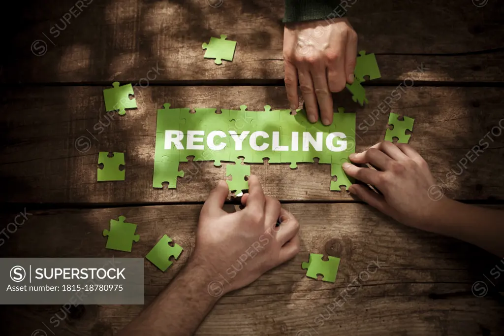 Friends joining puzzles with recycling word at table