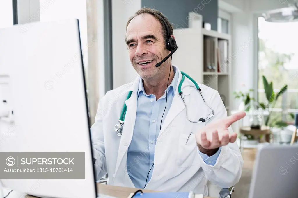 Smiling doctor gesturing on video call at clinic