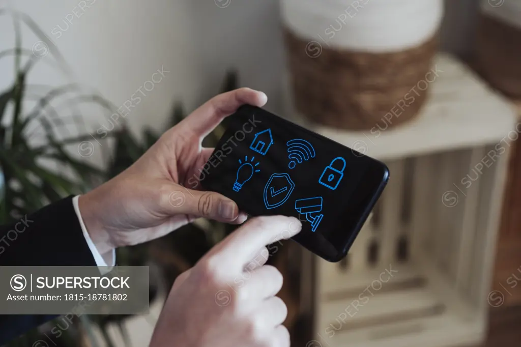 Businesswoman holding smart phone with home automation icons