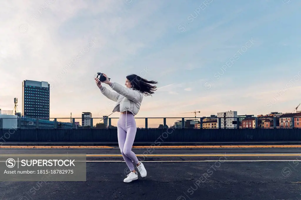 Influencer filming through camera on road at sunset