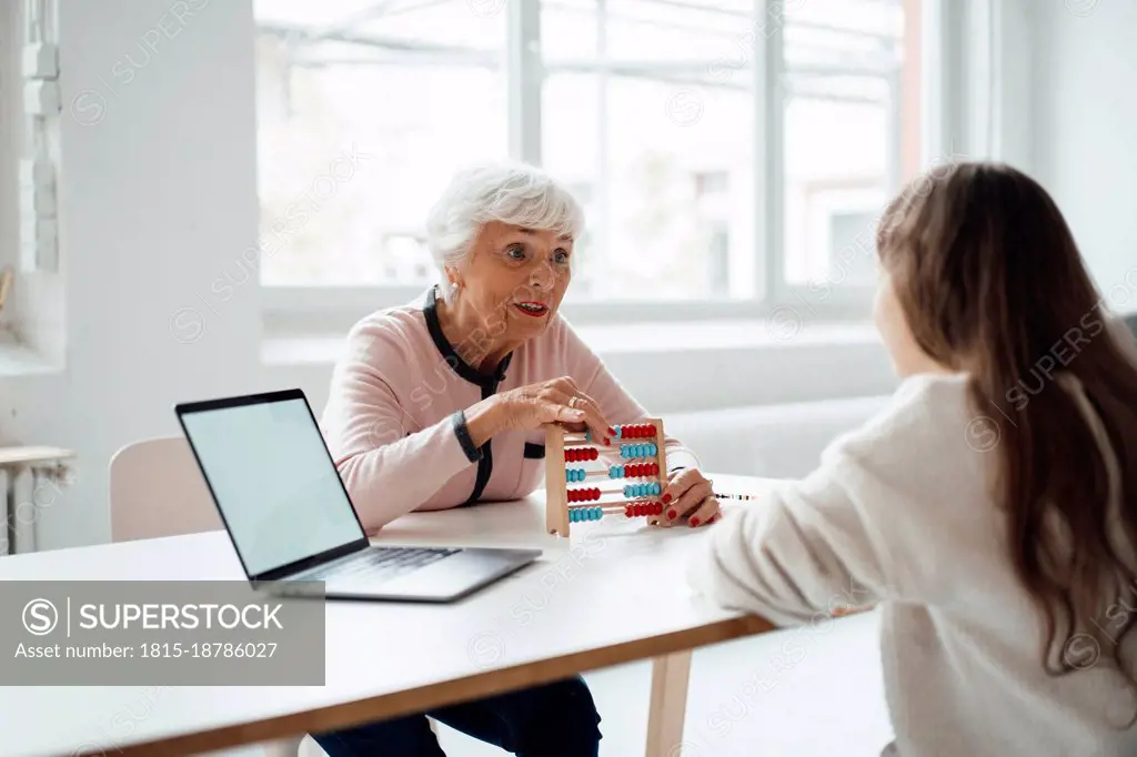 Grandmother with abacus talking to granddaughter at home