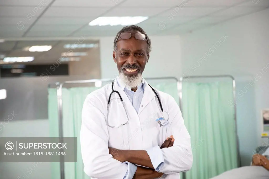 Confident male doctor with arms crossed in medical room