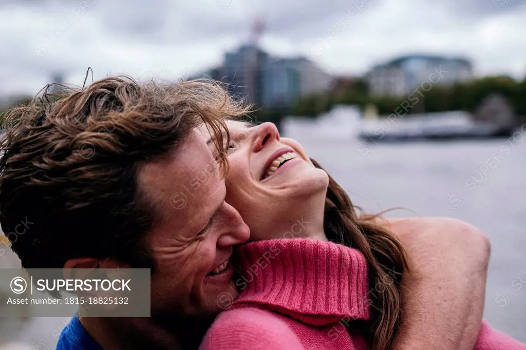 Man embracing cheerful woman from behind