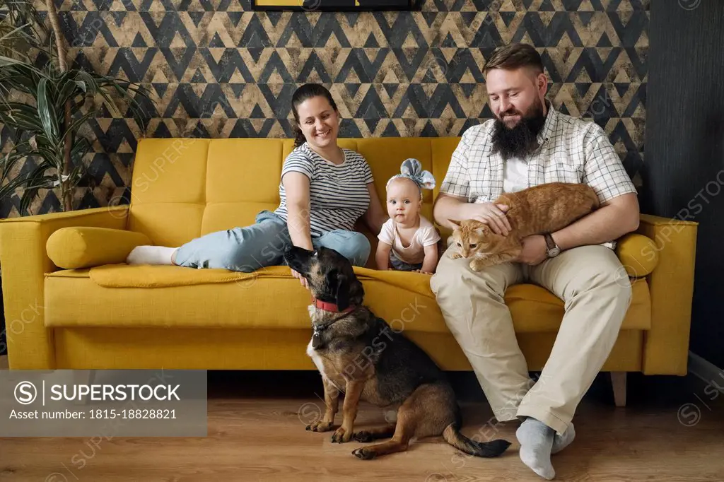 Smiling family with baby girl and pets in living room