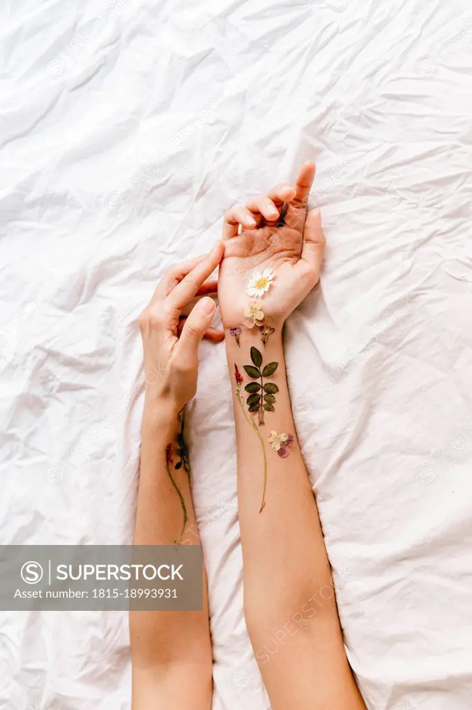 Woman's hands with flower arrangement on white sheet