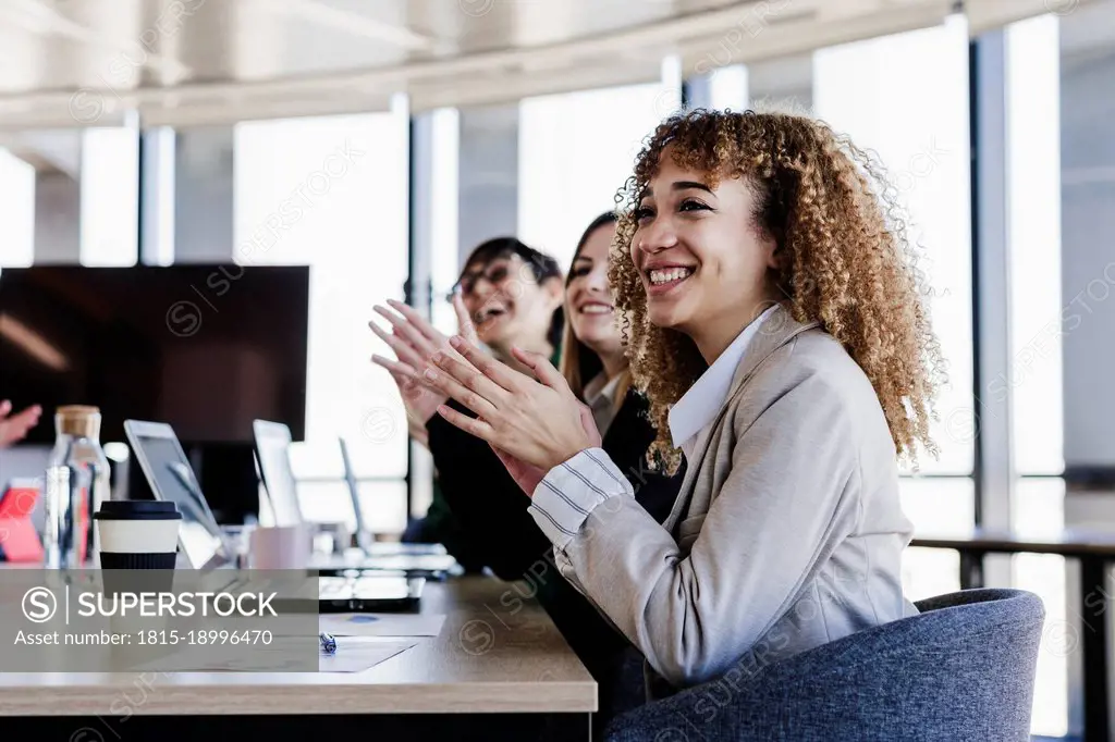 Cheerful business colleagues applauding in meeting at coworking office