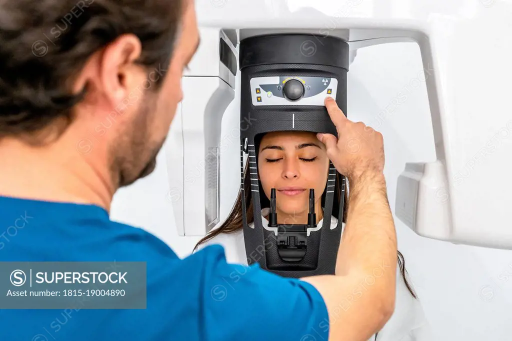 Doctor examining patient through machinery at medical clinic