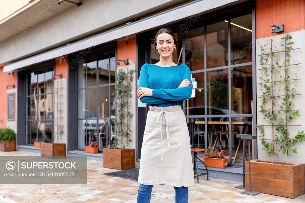 Smiling entrepreneur with arms crossed outside coffee shop