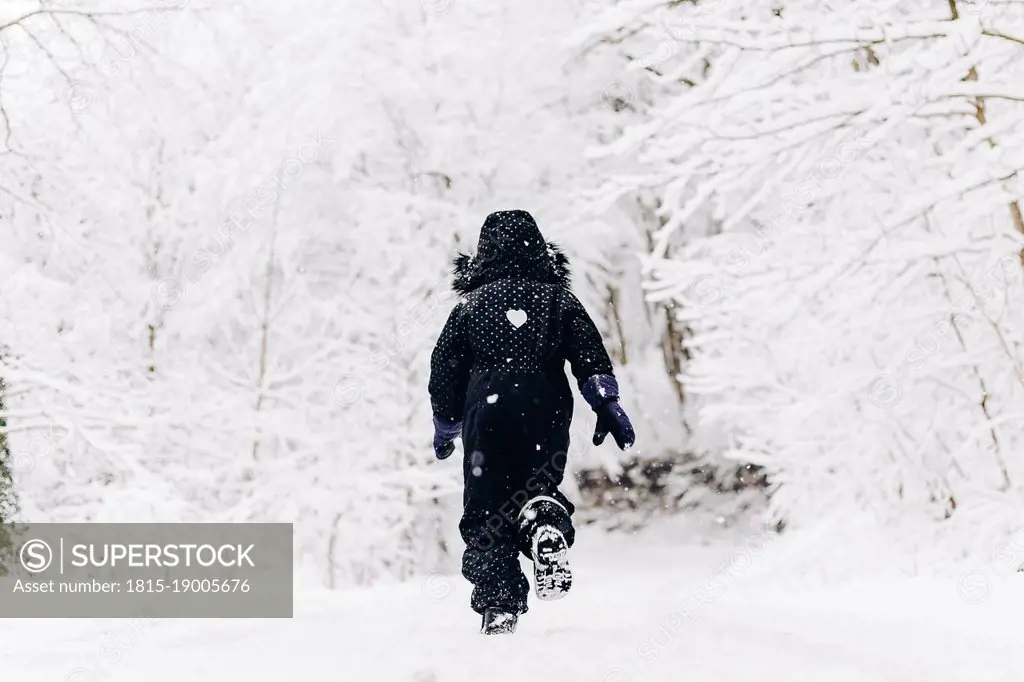 Girl running in snowy winter forest