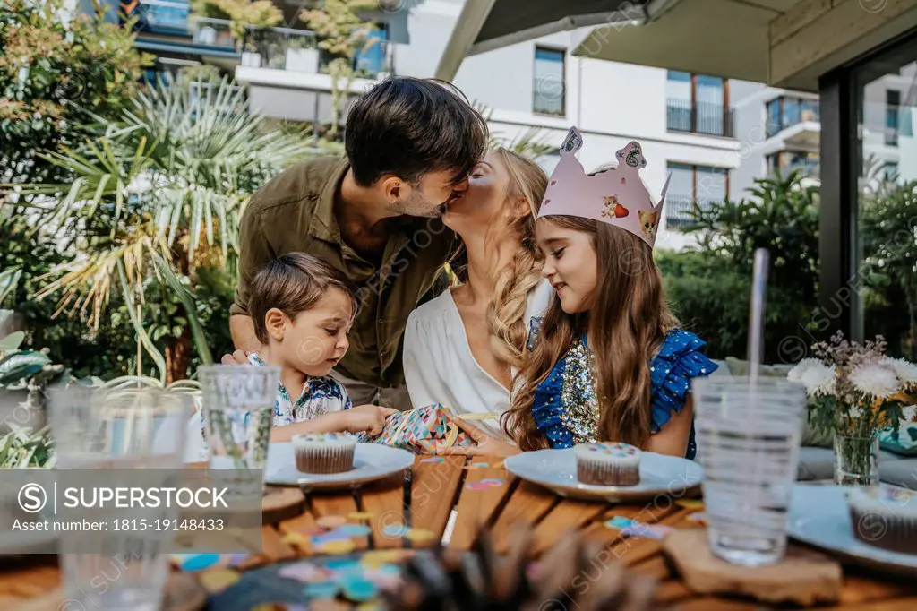 Parents kissing by children on party at back yard